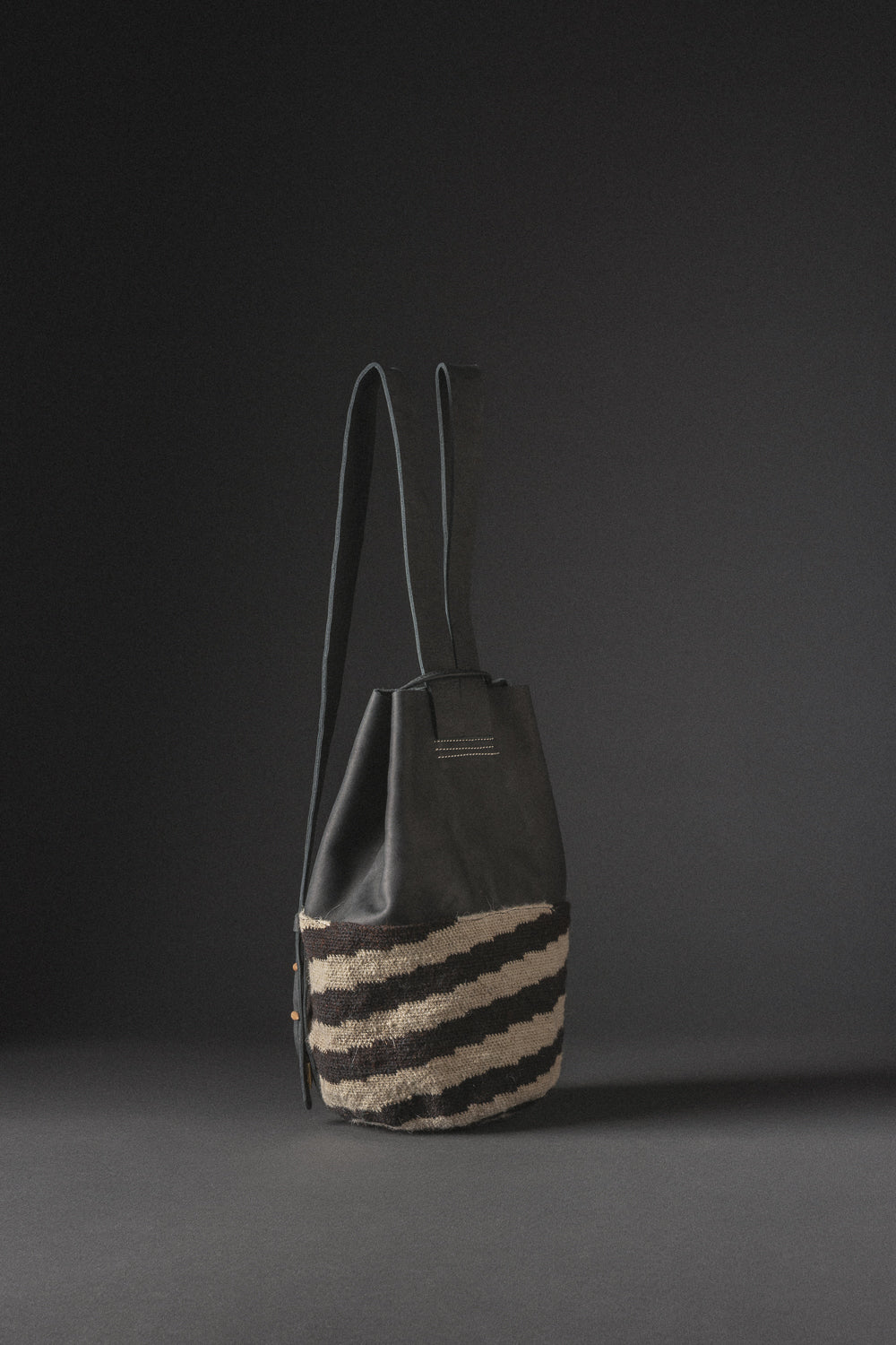 Mochila de cuero negro y tejido arhuaco, hecha a mano en Colombia.