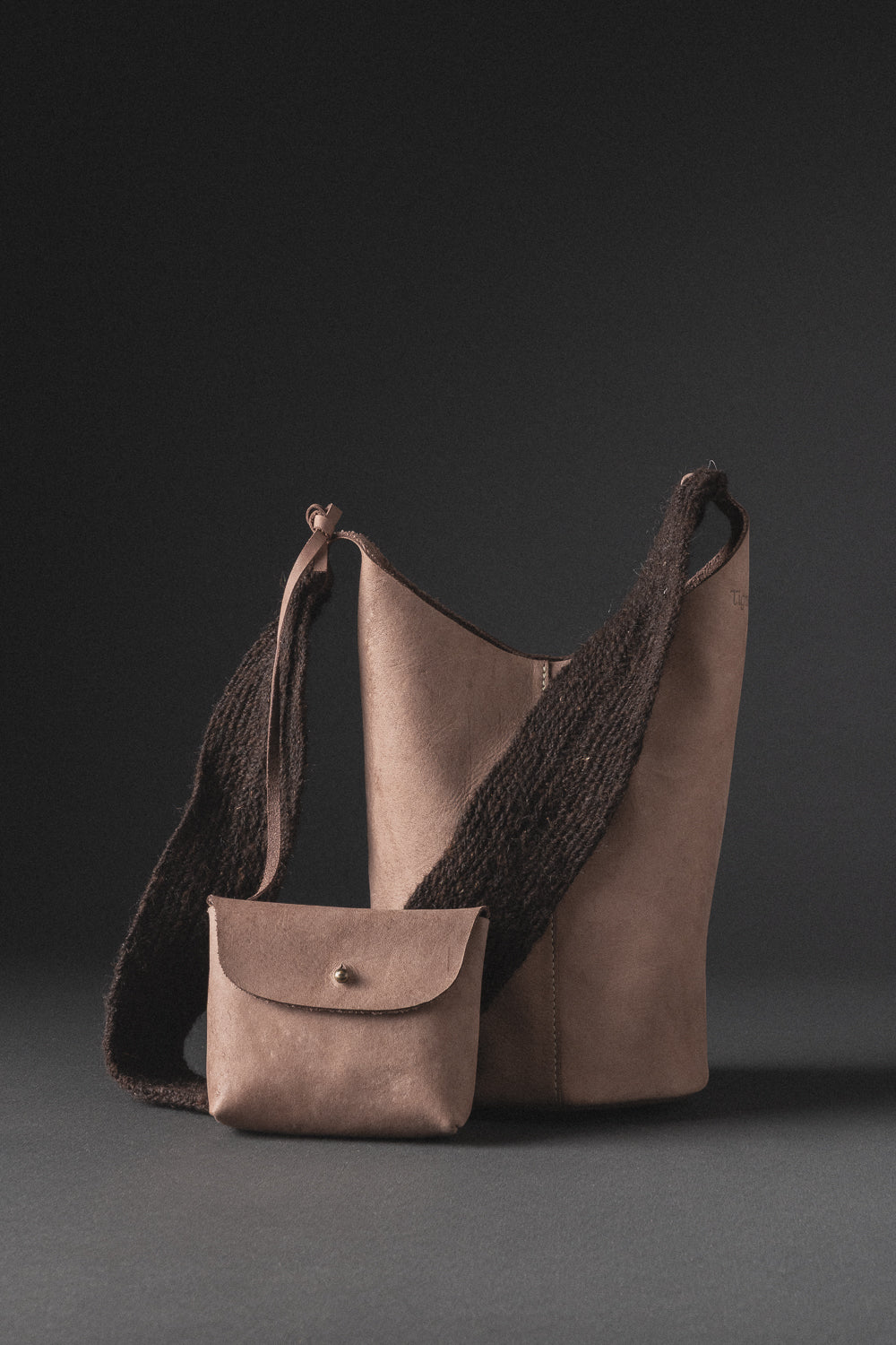 Bolso en cuero con cargadera de lana tejida a mano por la comunidad arhuaca, diseño artesanal colombiano