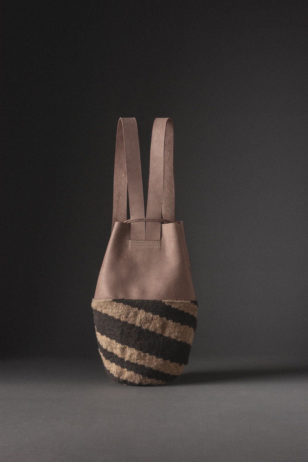 Morral en cuero marrón con tejido arhuaco en lana, pieza de diseño de artesanía colombiana.