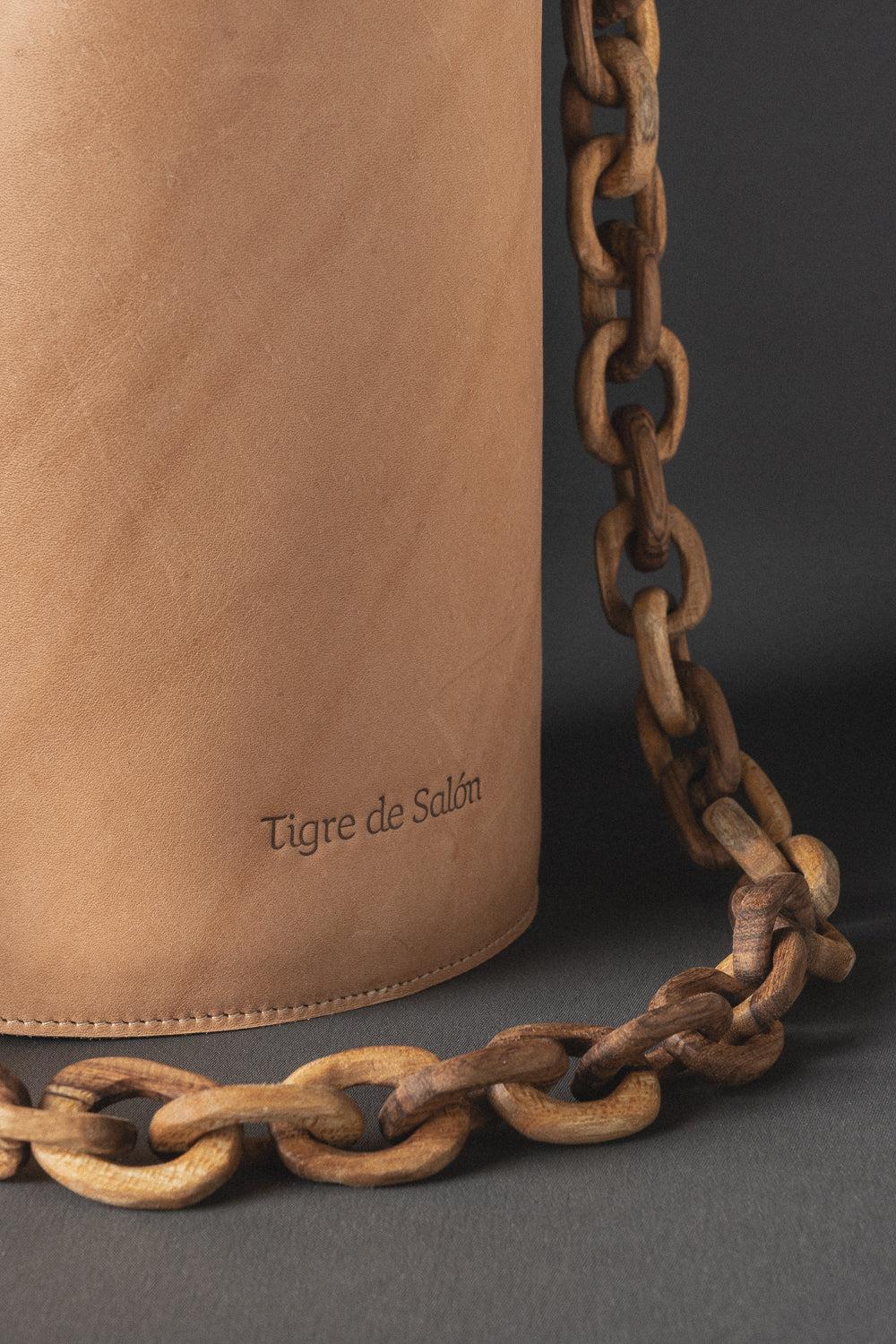 Bolso con cargadera de madera y cuerpo en cuero regenerativo, diseño contemporáneo y artesanal.